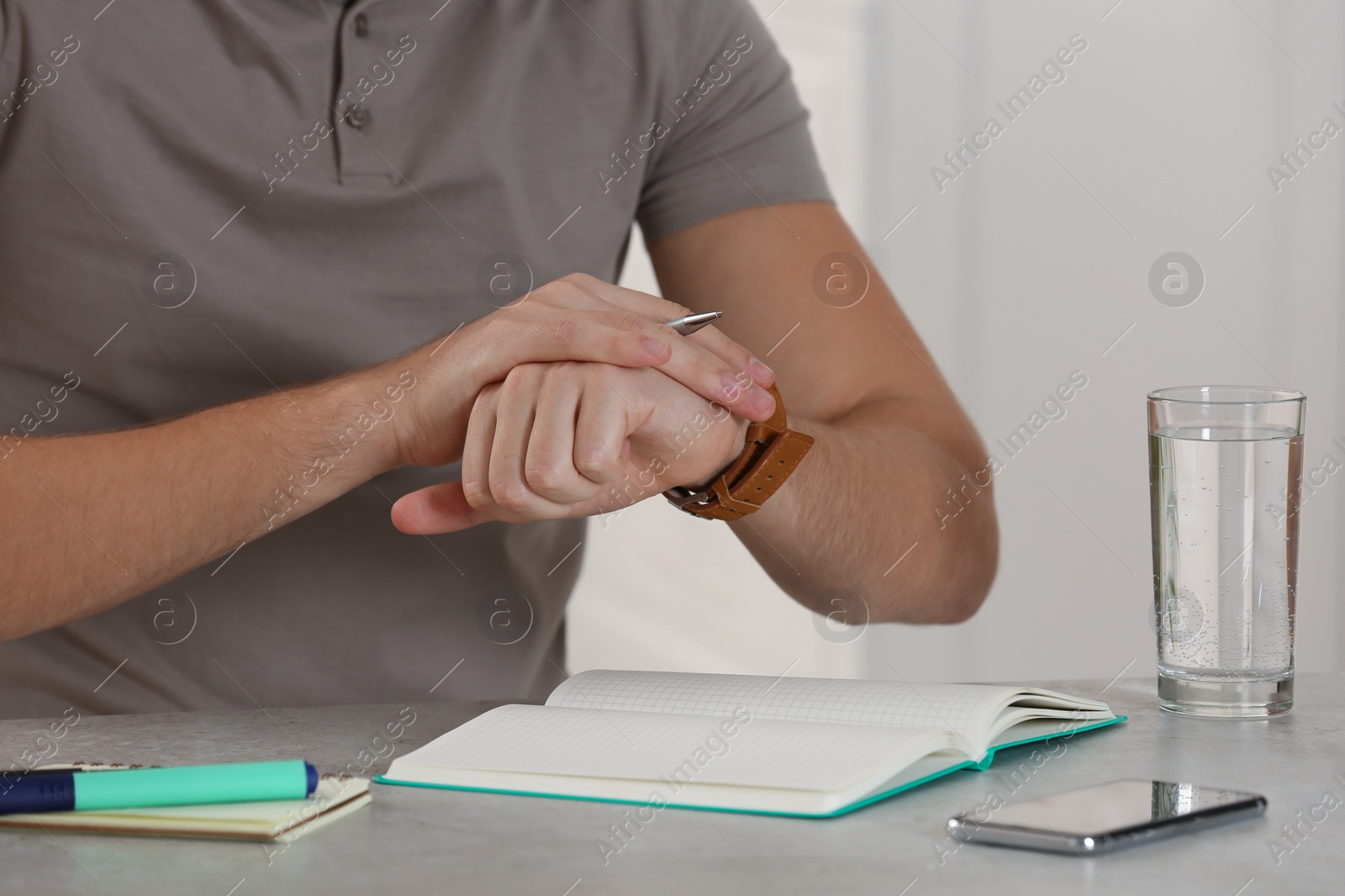 Photo of Man checking time at table indoors, closeup