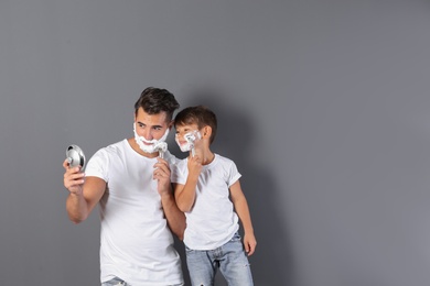 Photo of Father and son shaving on color background. Space for text