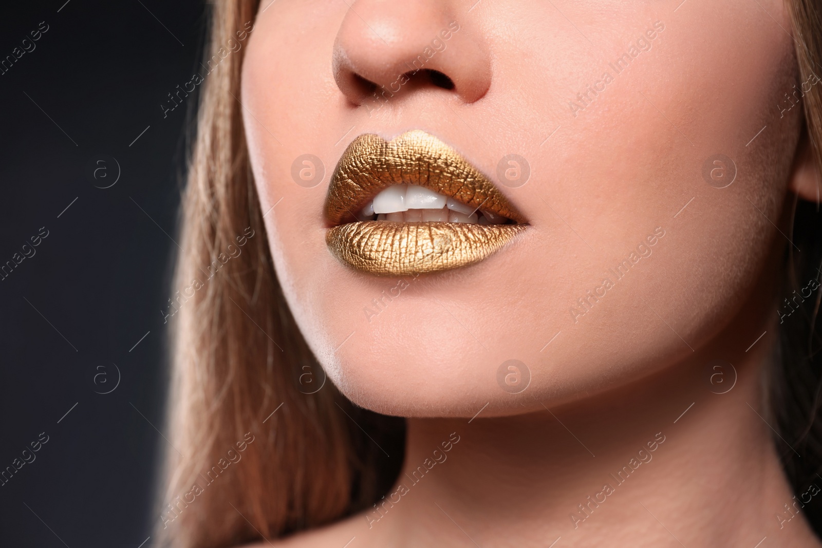 Photo of Woman with gold lipstick on grey background, closeup