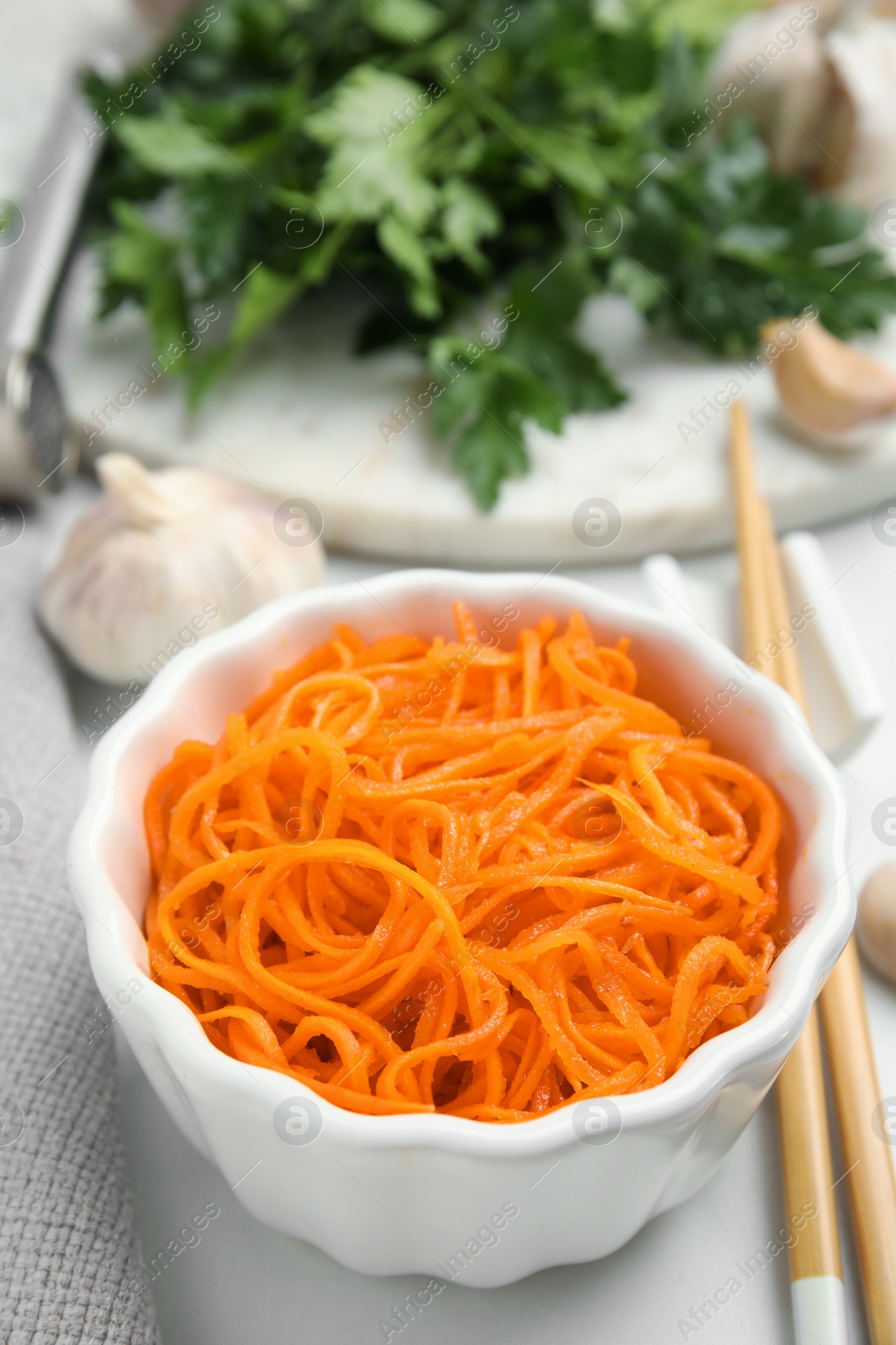 Photo of Delicious Korean carrot salad in bowl on white table