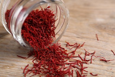 Photo of Aromatic saffron in glass jar on wooden table, closeup