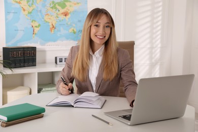 Happy manager working with laptop at desk in travel agency