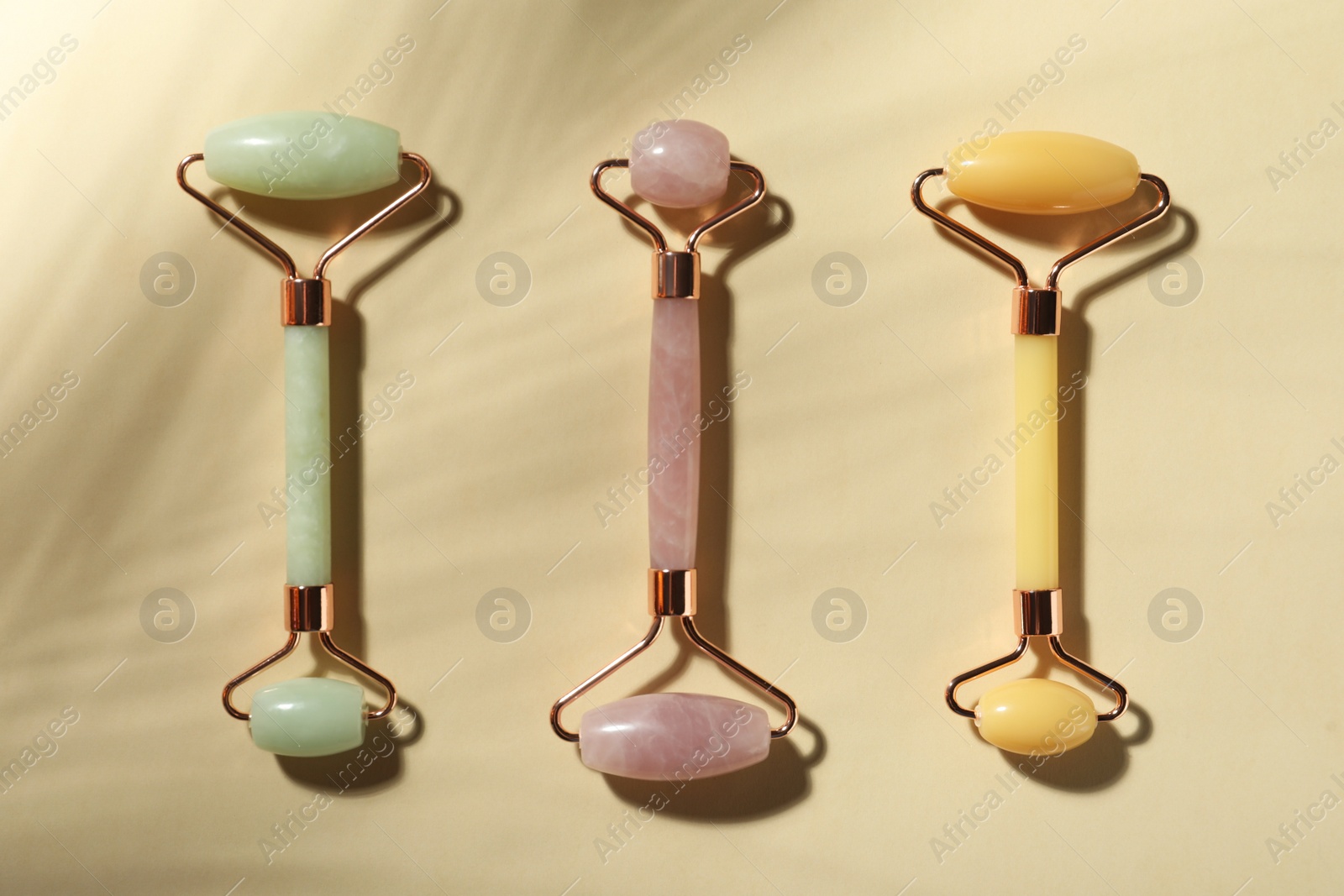 Photo of Different natural face rollers on beige background, flat lay