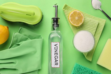 Photo of Eco friendly natural cleaners. Flat lay composition with bottle of vinegar on green background