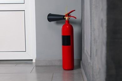 Photo of Red fire extinguisher near grey wall, space for text