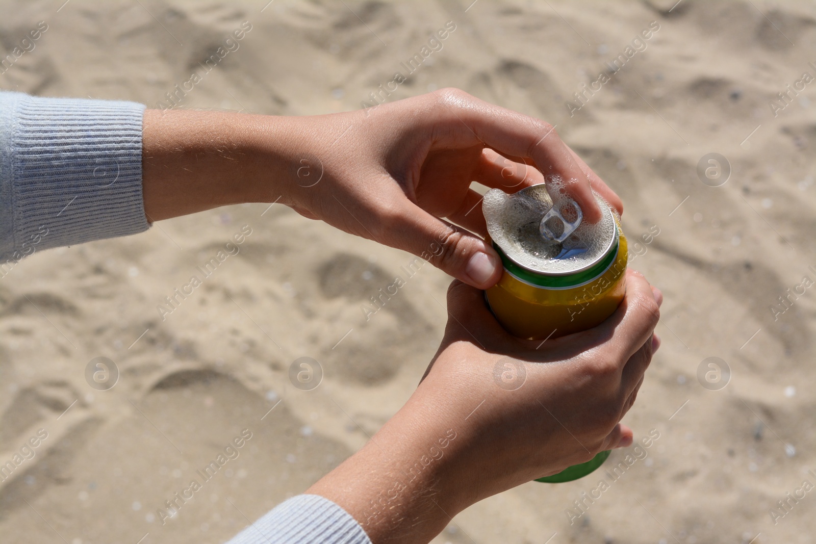 Photo of Woman opening can with sparkling drink at beach, closeup