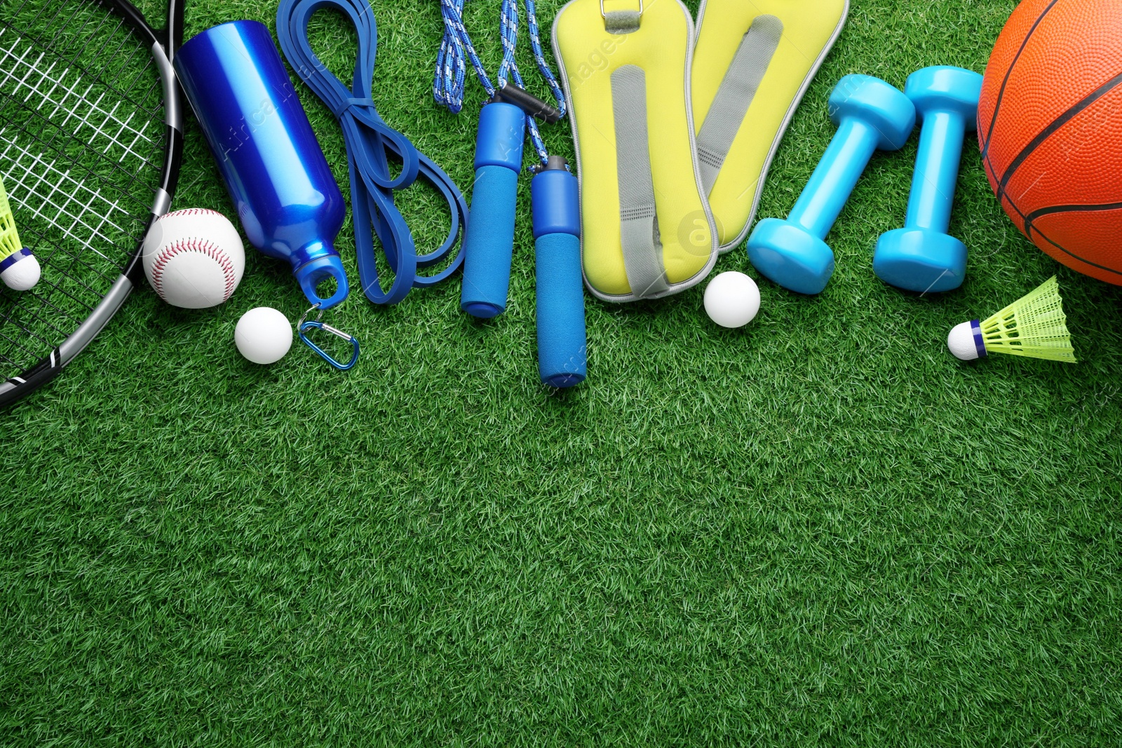 Photo of Set of different colorful sports equipment on green grass, flat lay. Space for text