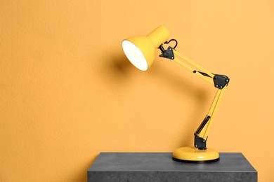 Photo of Stylish lamp on table against color background. Space for text