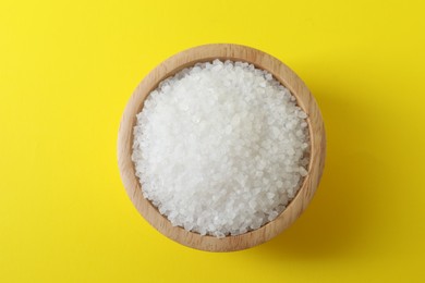 Photo of Organic white salt in bowl on yellow background, top view