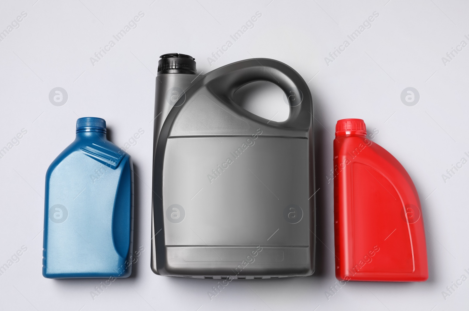 Photo of Motor oil in different canisters on light background, flat lay