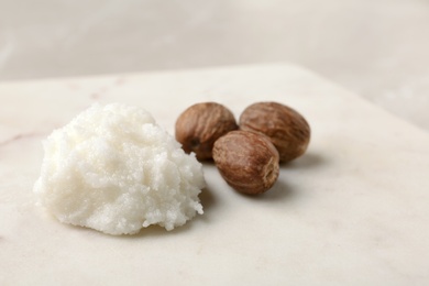 Photo of Shea butter and nuts on board, closeup. Space for text