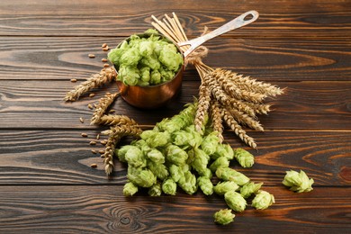 Photo of Fresh hop flowers and wheat ears on wooden table