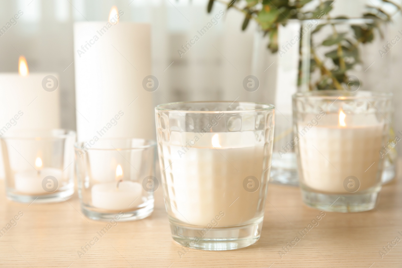 Photo of Burning aromatic candles on wooden table. Interior decor