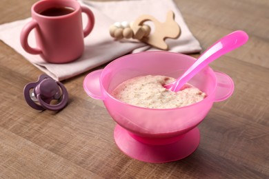 Baby food. Puree in bowl, drink, toy and soother on wooden table