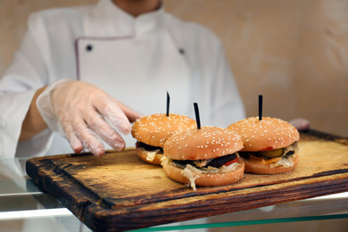 School canteen worker with burgers at serving line, closeup. Tasty food