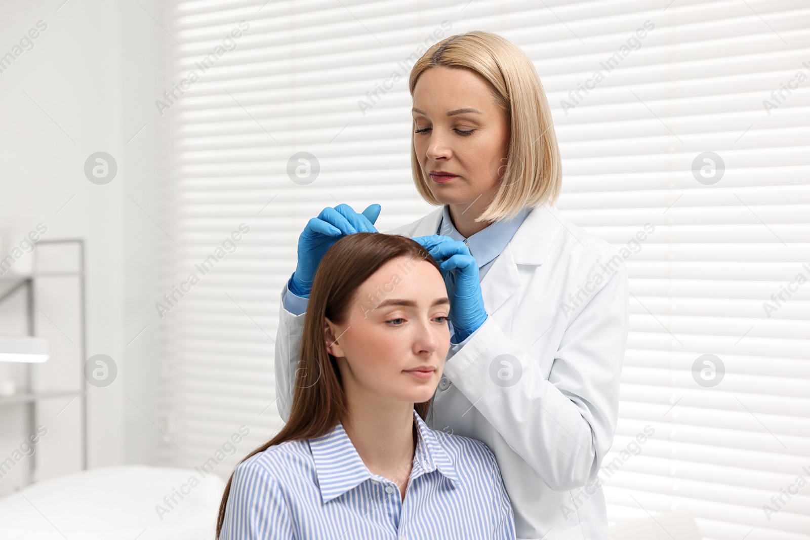 Photo of Trichologist in gloves examining patient`s hair in clinic