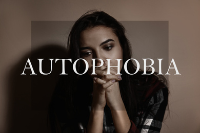 Image of Depressed young woman near brown wall. Autophobia - fear of isolation