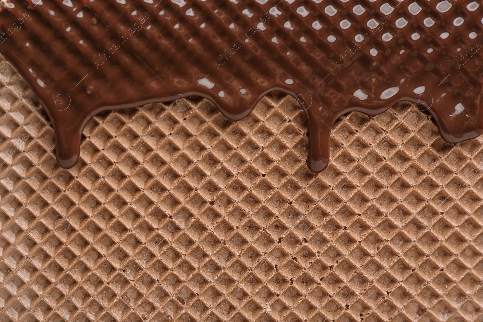 Photo of Hot dark chocolate on wafer, closeup. Crispy food