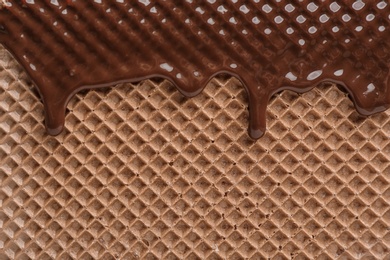 Hot dark chocolate on wafer, closeup. Crispy food