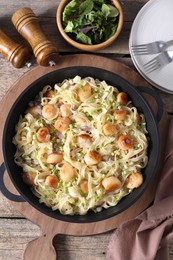 Photo of Delicious scallop pasta with onion served on wooden table, flat lay