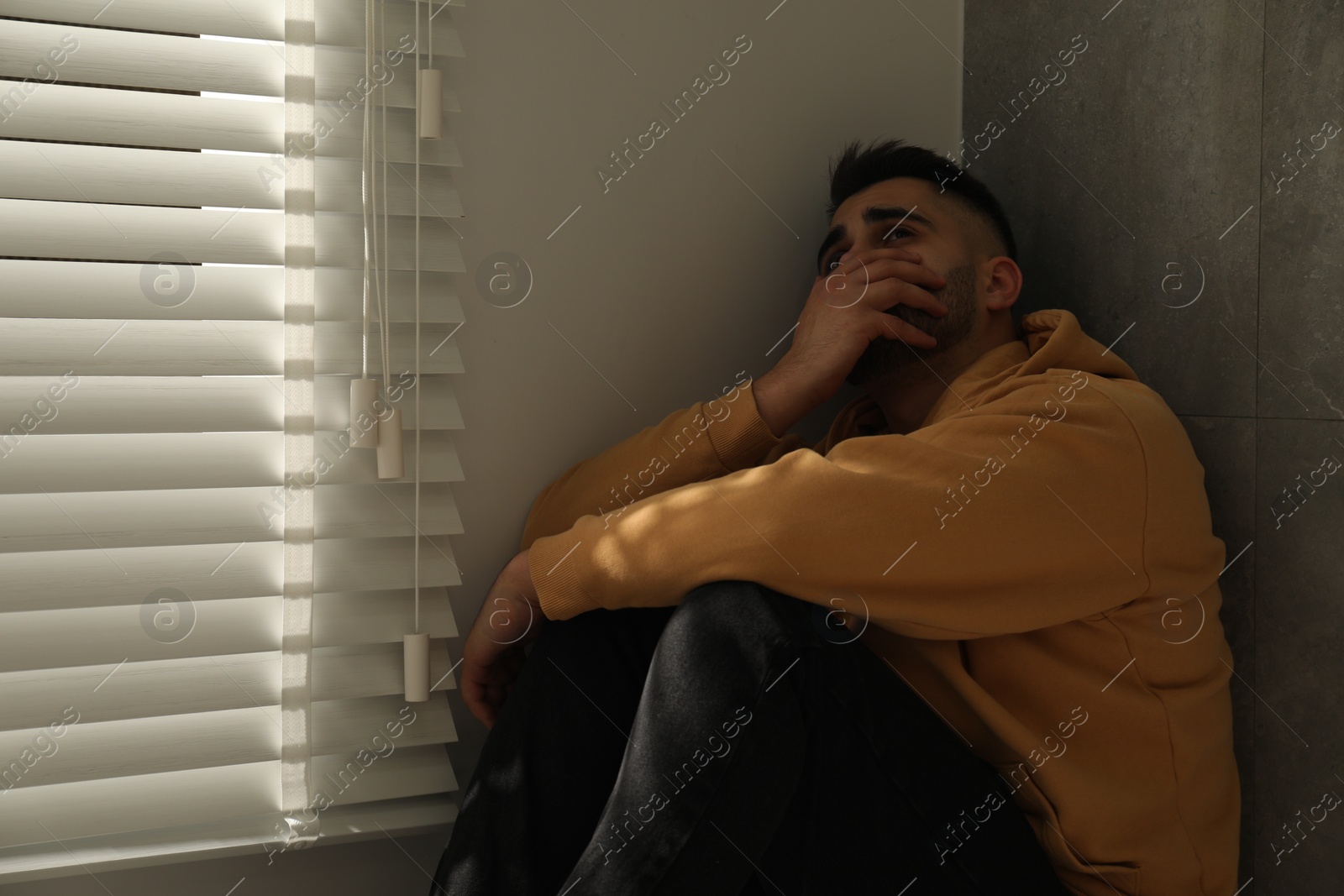 Photo of Sad man sitting near window. Space for text