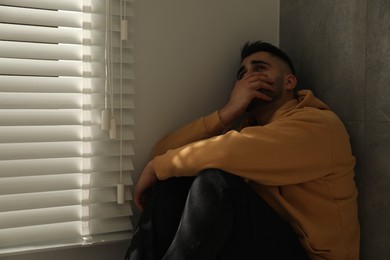 Photo of Sad man sitting near window. Space for text