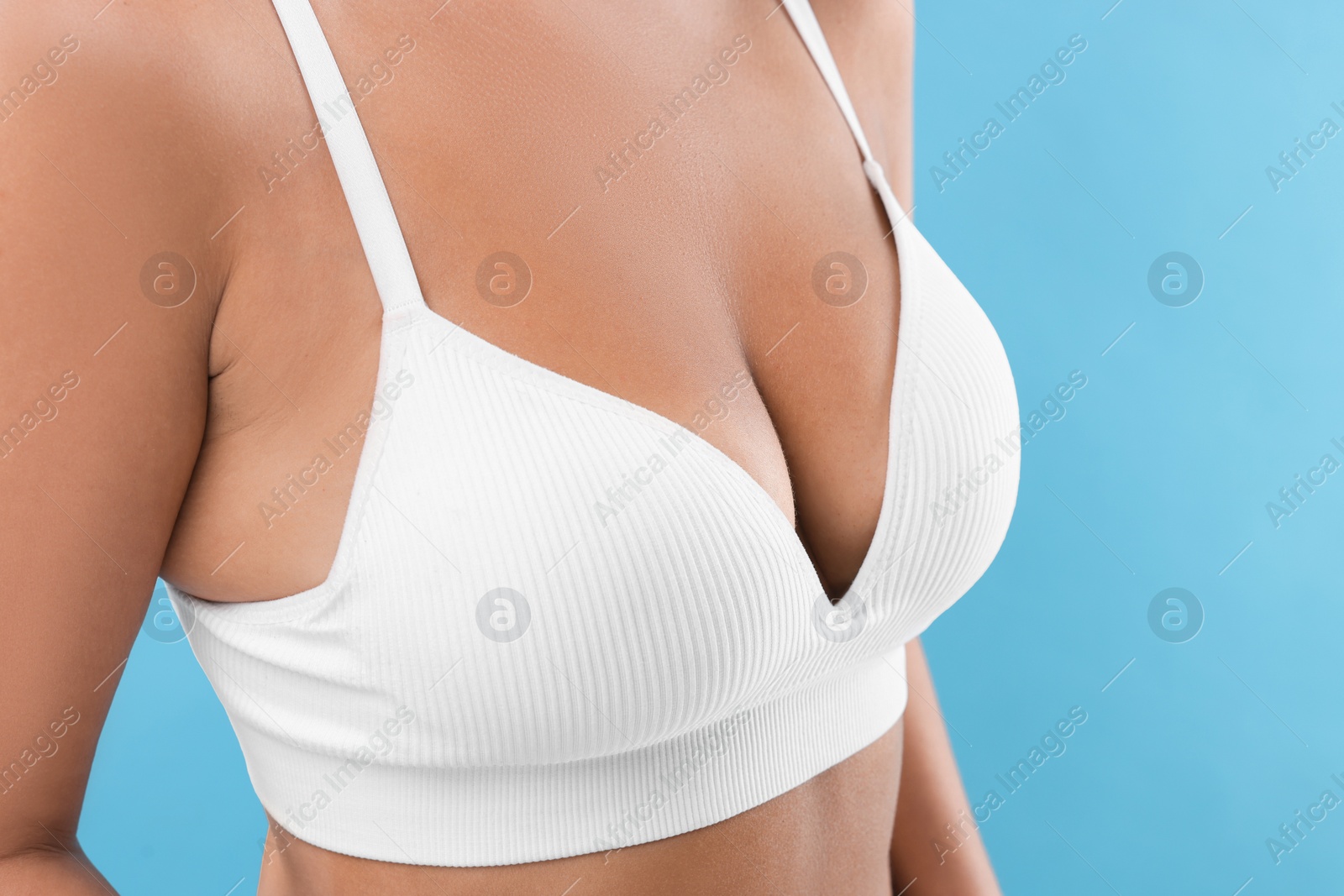 Photo of Woman with beautiful breast on light blue background, closeup