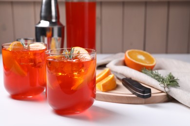 Aperol spritz cocktail, rosemary and orange slices on white wooden table