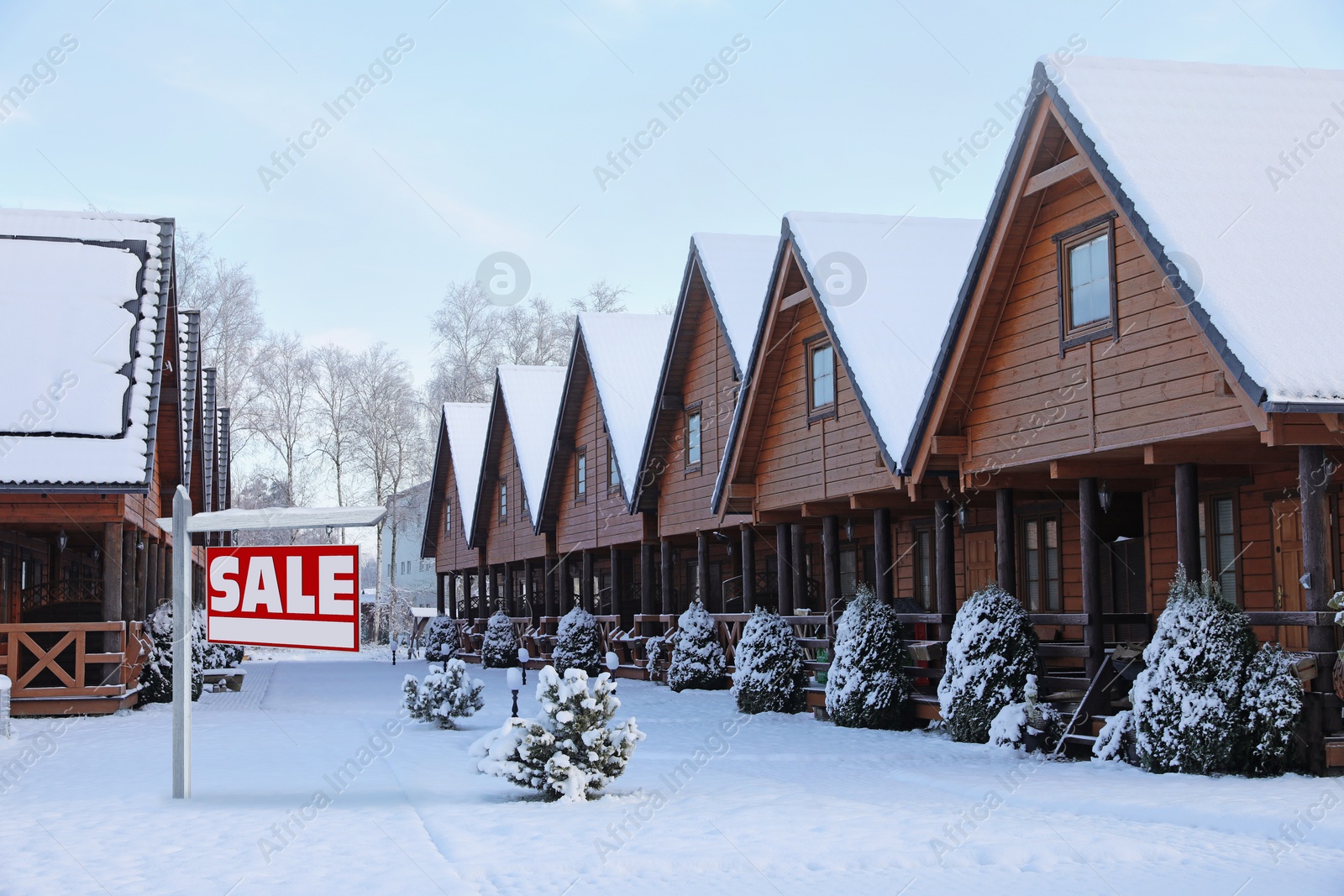 Image of Sale sign near beautiful house outdoors in winter. Red signboard with word