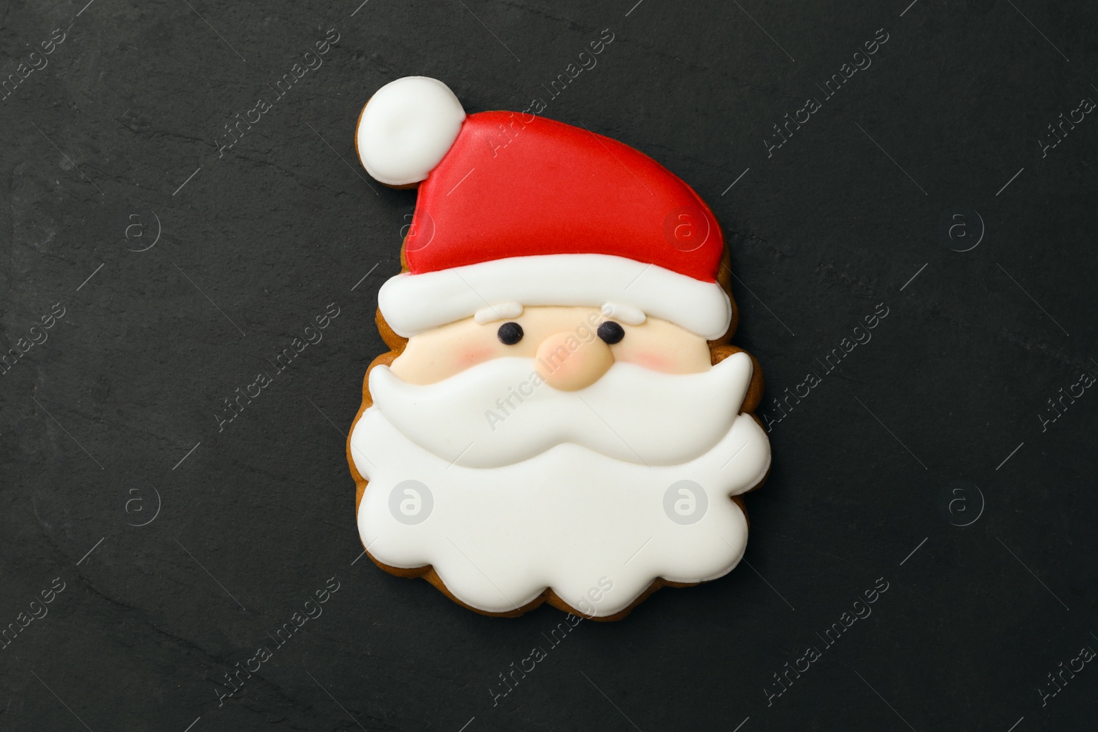 Photo of Santa Claus shaped Christmas cookie on black table, top view