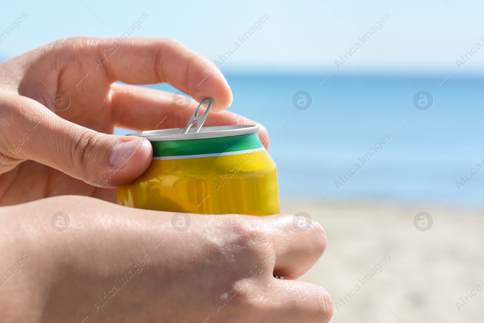 Photo of Woman opening can with sparkling drink at beach, closeup. Space for text