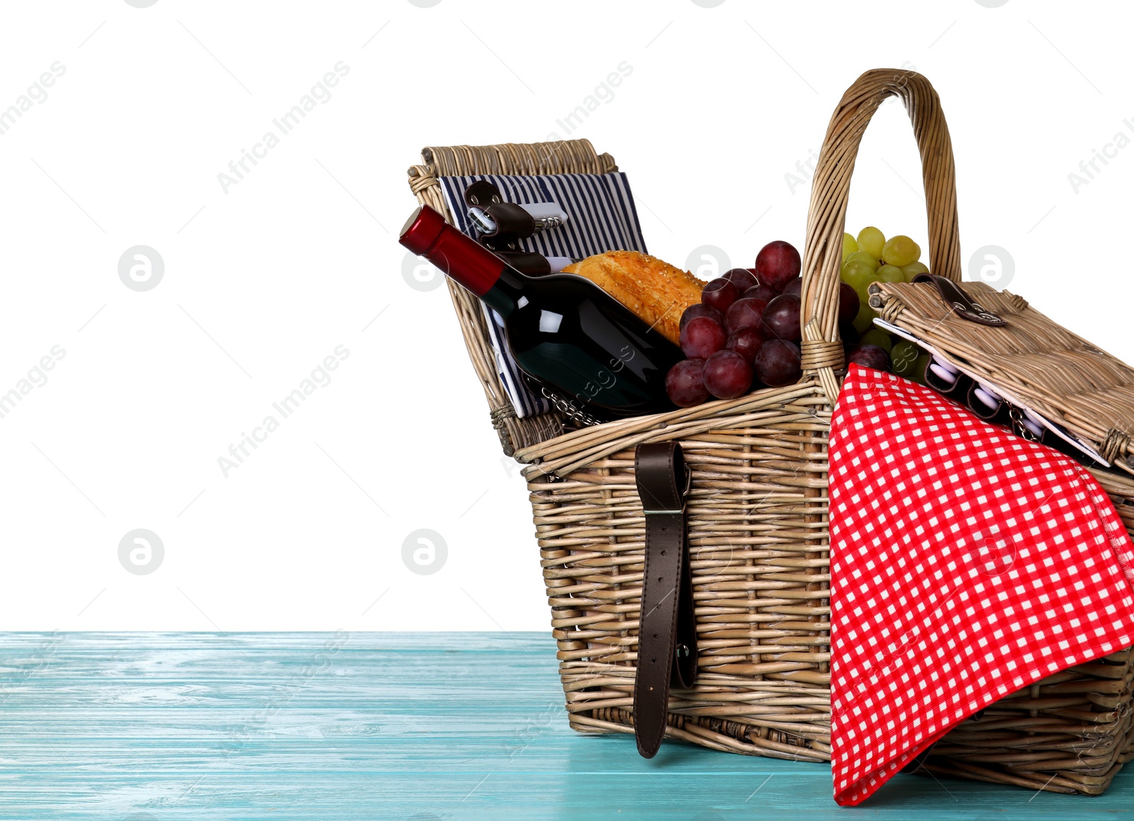 Photo of Wicker picnic basket with wine and different products on wooden table against white background, space for text
