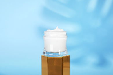 Photo of Open jar of cream on display against blue background