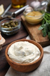 Photo of Tasty tartar sauce and ingredients on wooden table