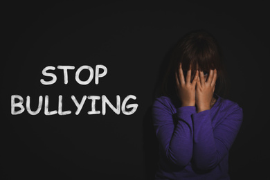 Image of Message STOP BULLYING and abused little girl crying near black wall