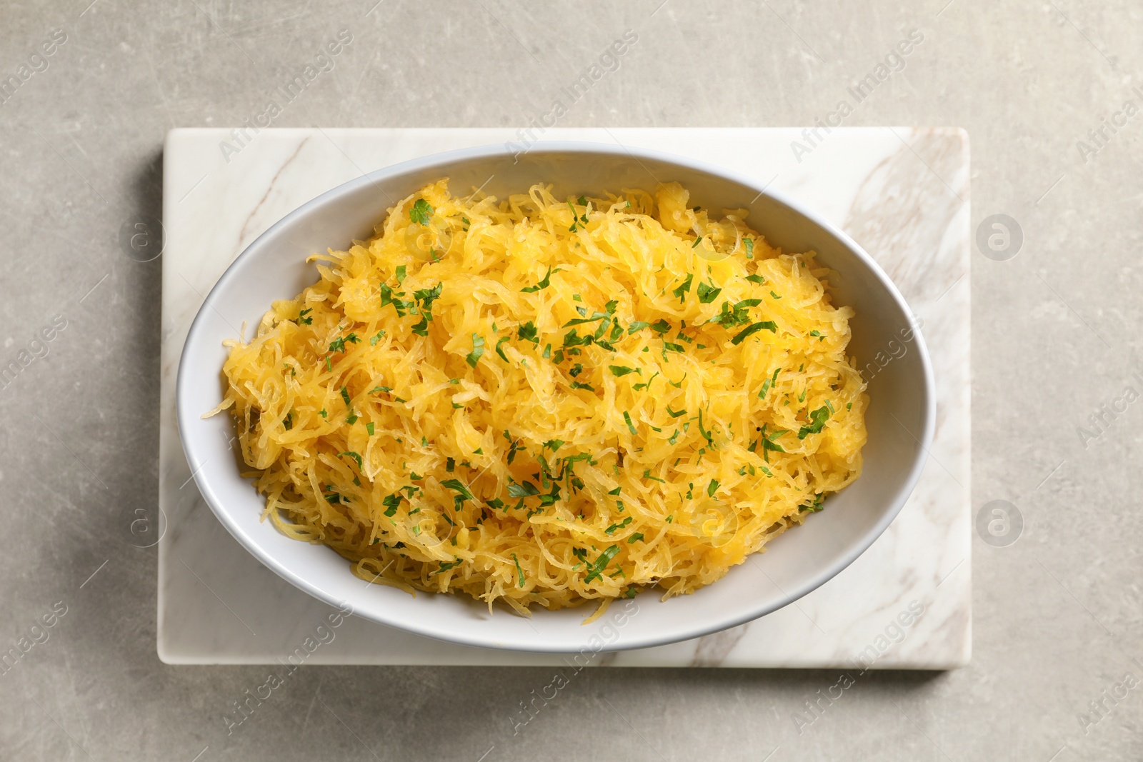 Photo of Bowl with cooked spaghetti squash on light background, top view