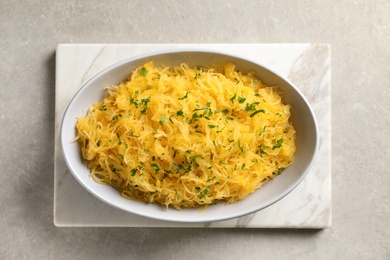 Bowl with cooked spaghetti squash on light background, top view