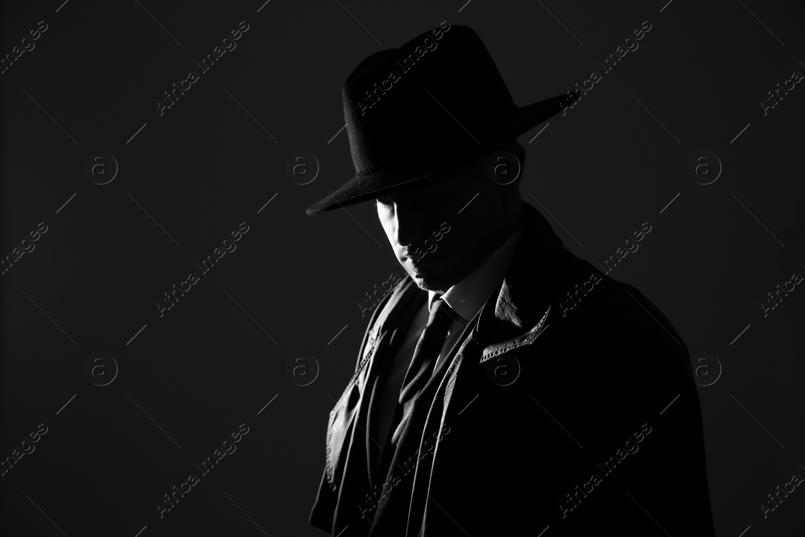 Photo of Old fashioned detective in hat on dark background, black and white effect. Space for text