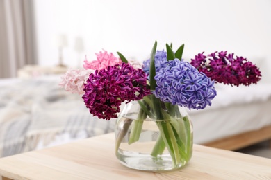 Beautiful hyacinths in glass vase on table indoors. Spring flowers