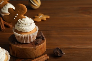 Photo of Tasty Christmas cupcake with gingerbread man cookie on wooden table, space for text