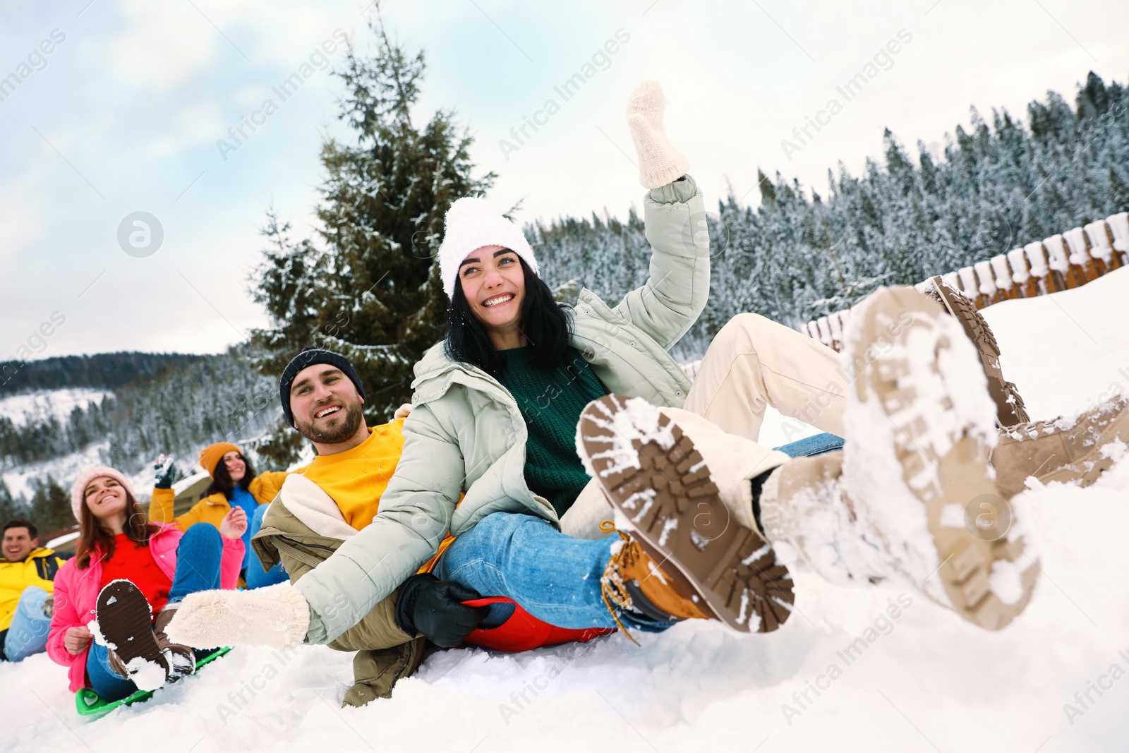 Photo of Group of friends having fun and sledding on snowy day. Winter vacation