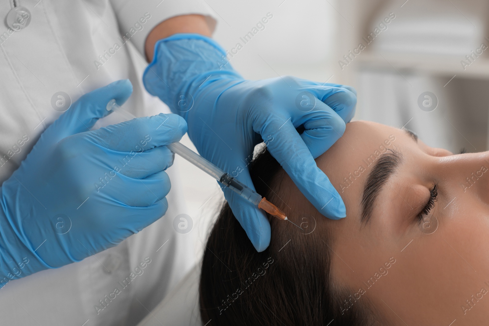 Photo of Trichologist giving injection to patient in clinic, closeup