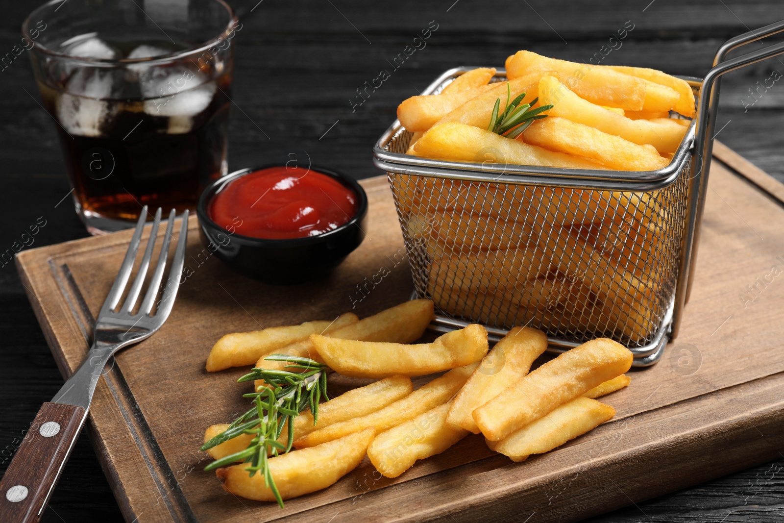 Photo of Tasty french fries and ketchup served on dark wooden table, closeup