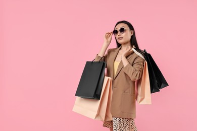 Beautiful woman with shopping bags on pink background. Space for text