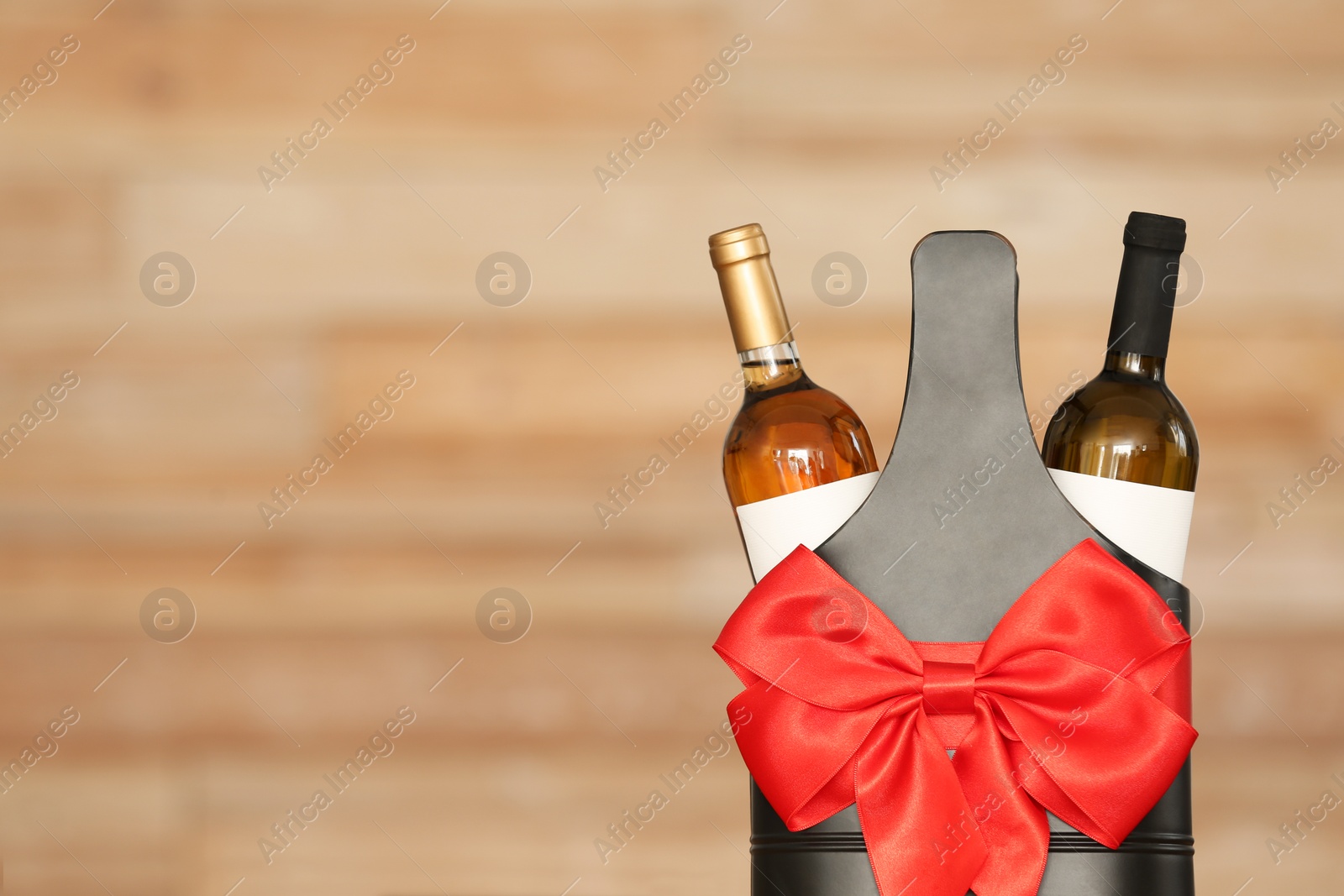 Photo of Festive package with bottles of wine against blurred background. Space for text