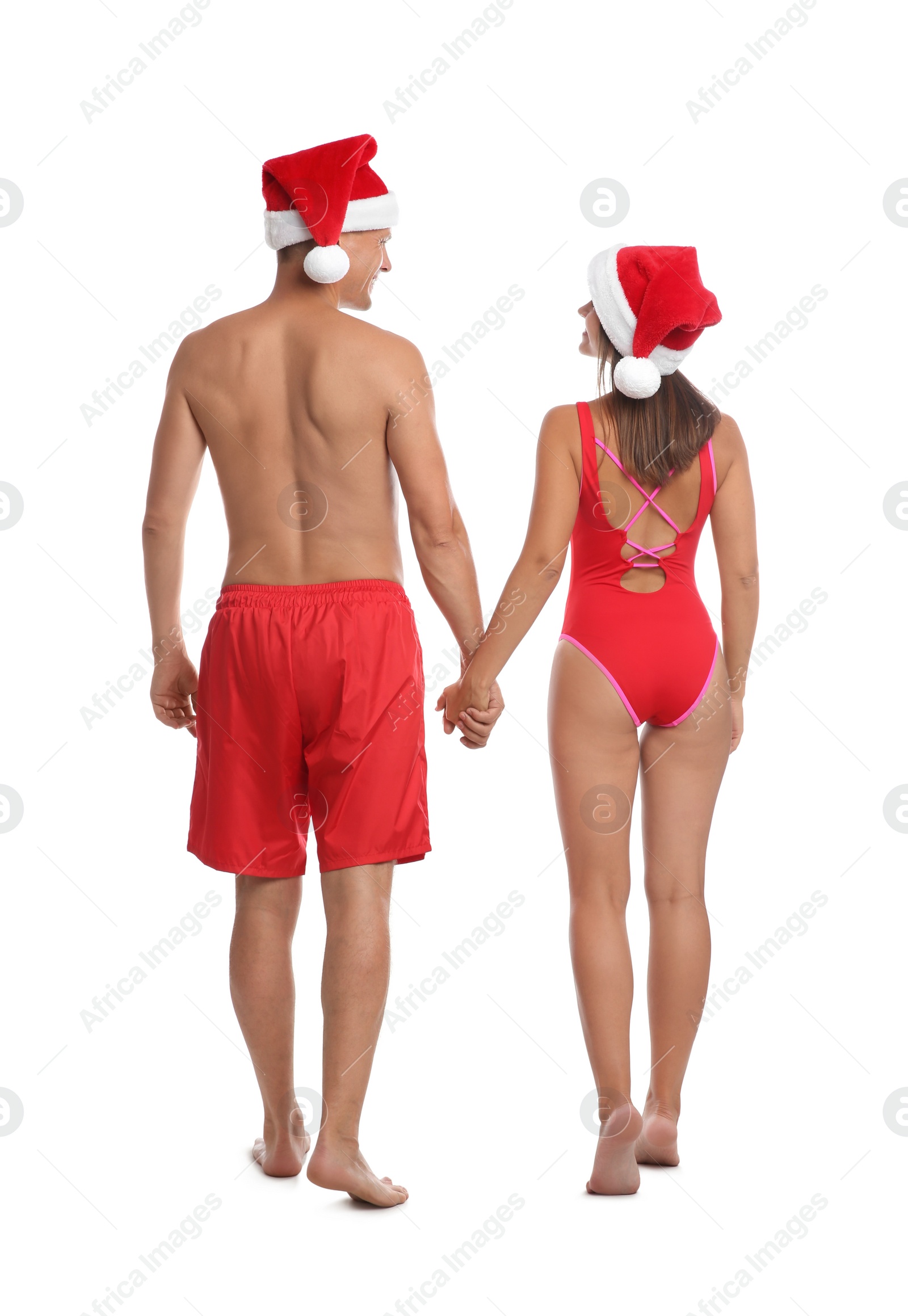 Photo of Lovely couple with Santa hats together on white background, back view. Christmas vacation