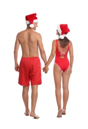 Lovely couple with Santa hats together on white background, back view. Christmas vacation