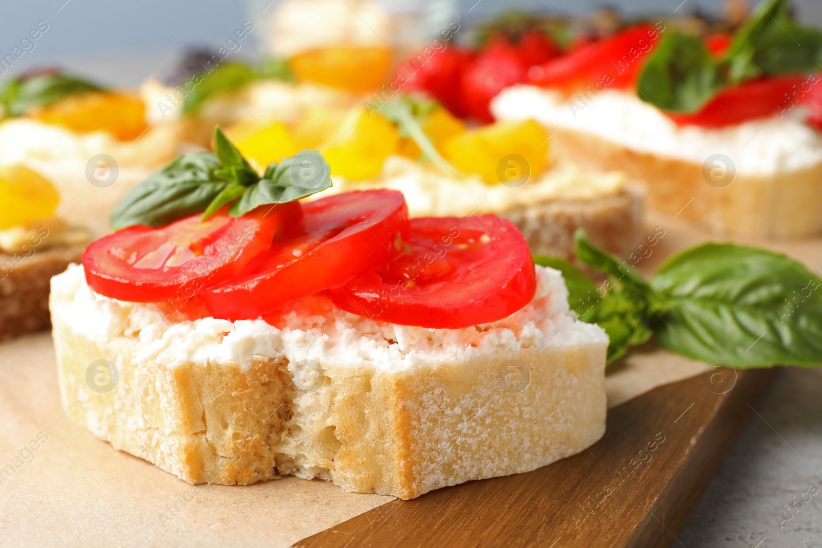 Photo of Tasty fresh tomato bruschettas on wooden board, closeup