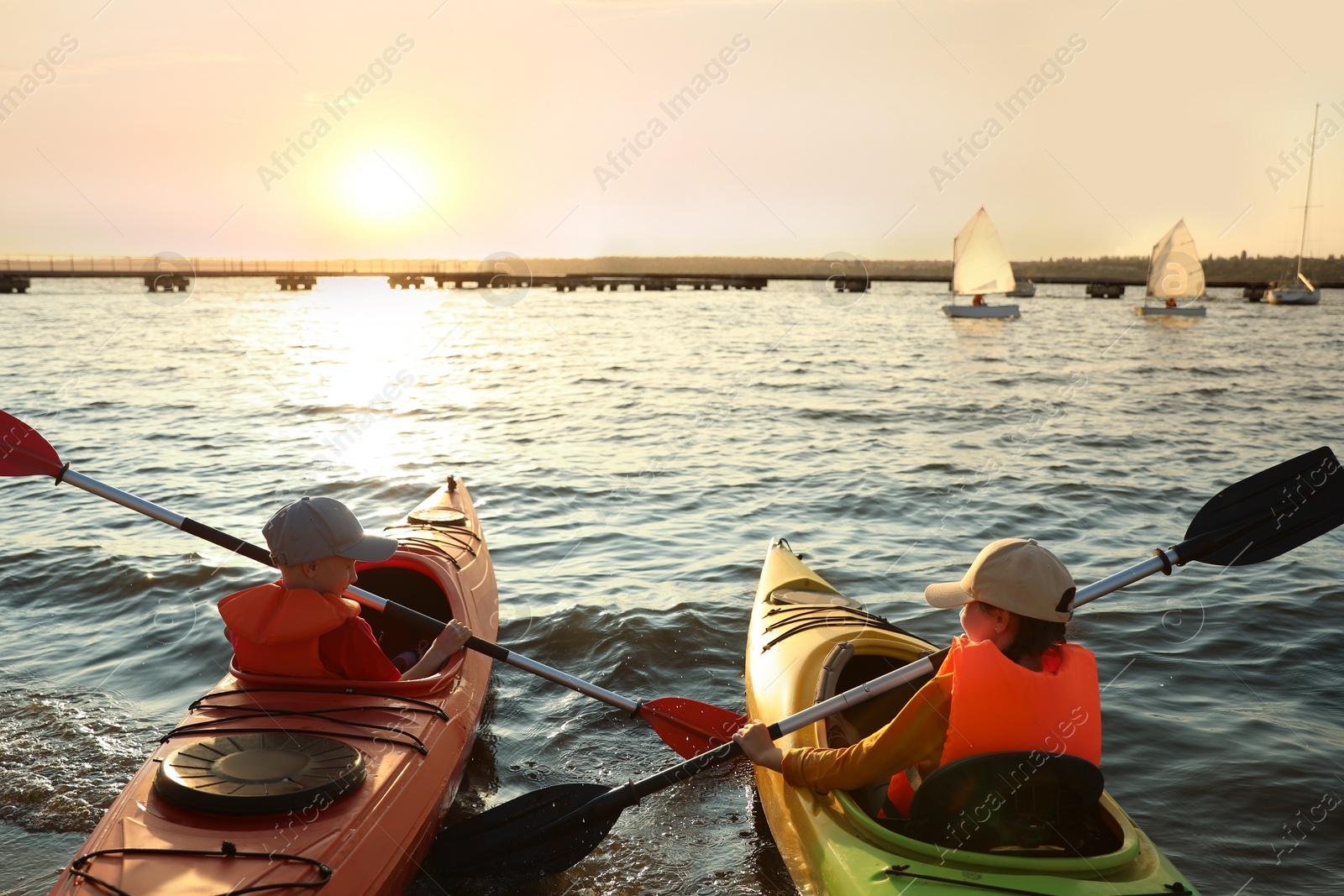 Photo of Little children kayaking on river, back view. Summer camp activity