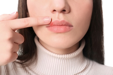 Young woman pointing on lips against white background, closeup